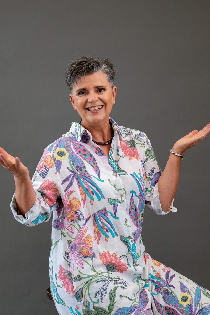 Businessportrait in bunter Blumenbluse vor grauem Hintergrund