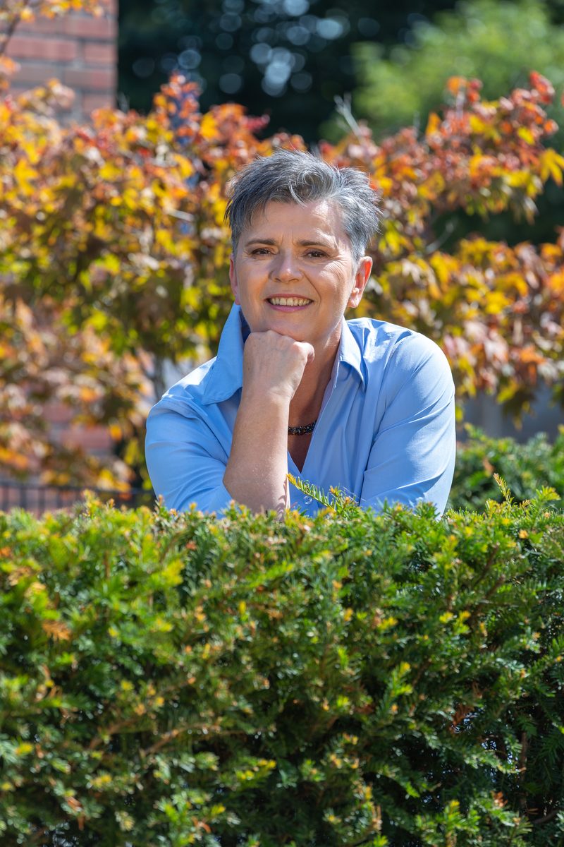 Businessportrait an einer Gartenhecke im Sonnenlicht