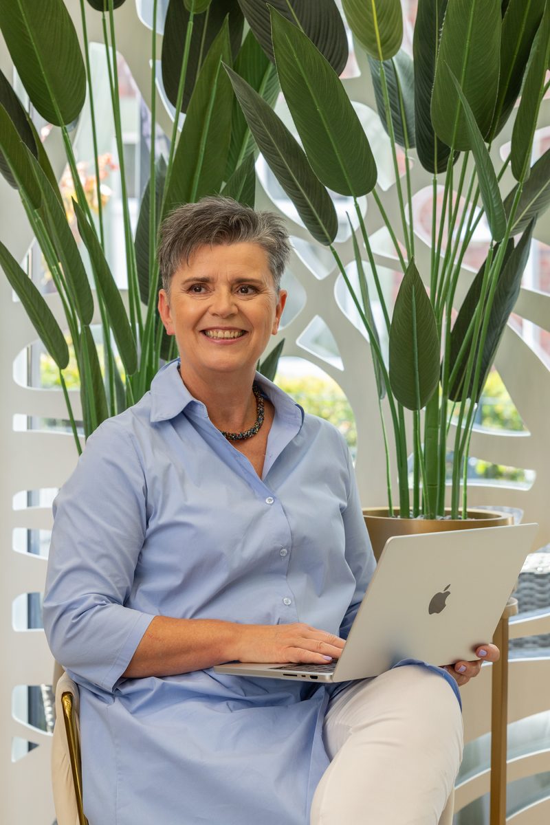 Businessportrait mit Laptop vor großen Grünpflanzen