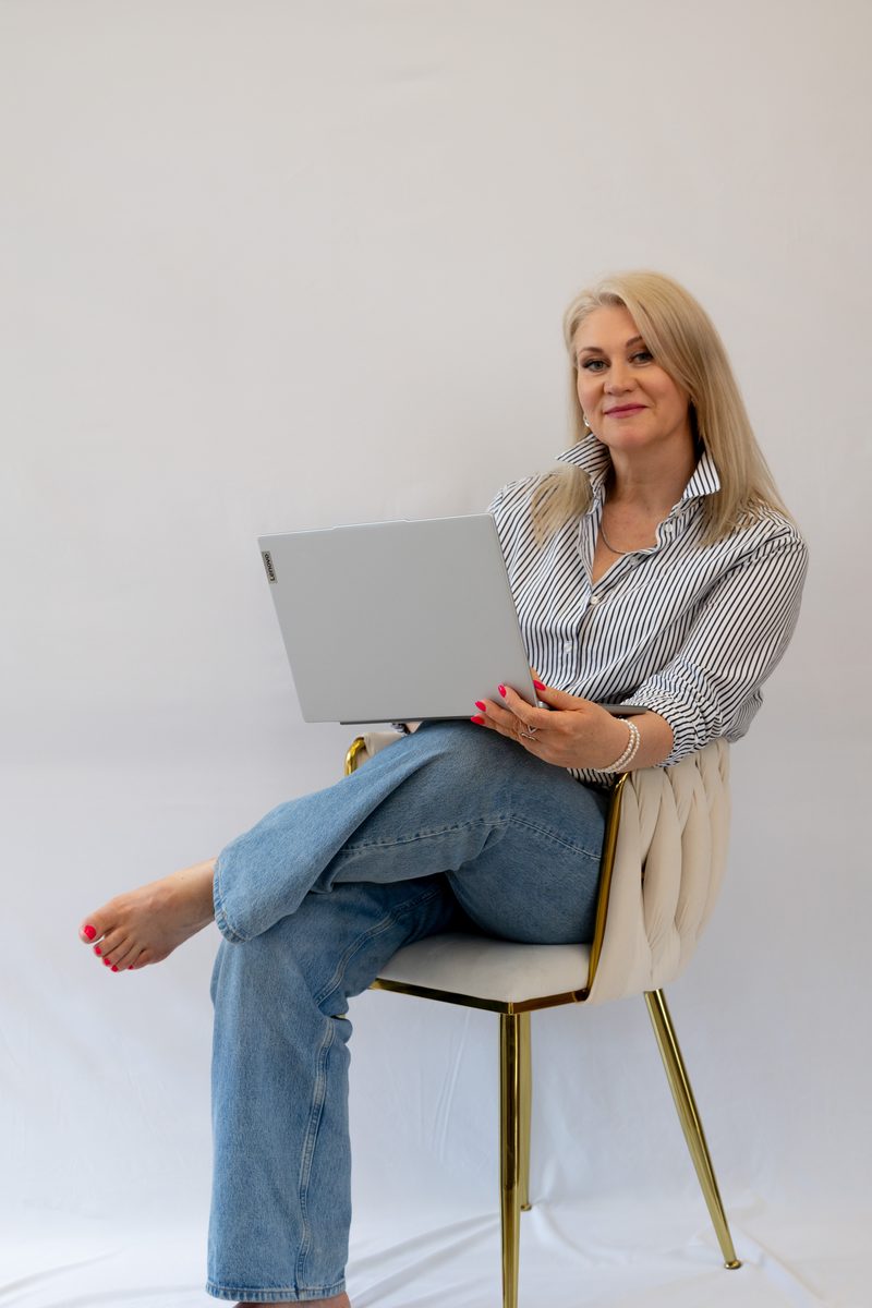 Businessportrait mit Laptop auf einem Stuhl vor weißem Hintergrund