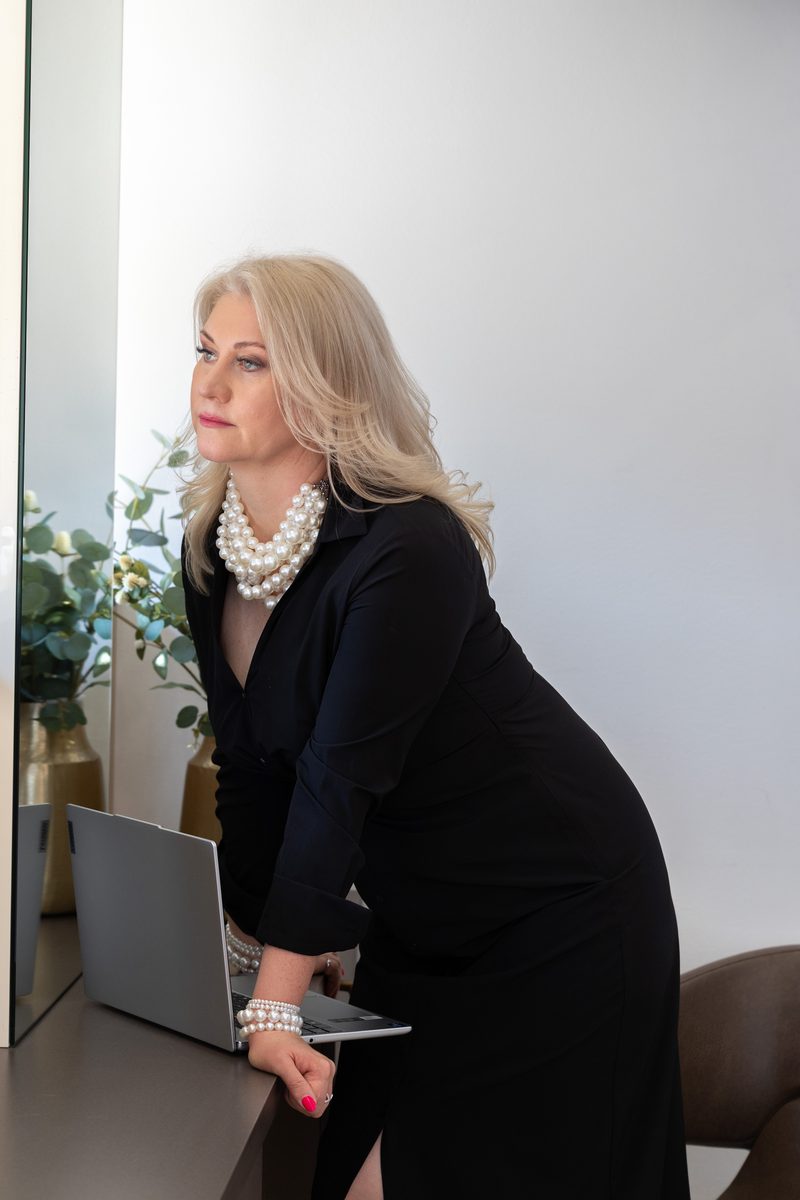 Businessportrait im schwarzen Kleid mit Perlenkette am Laptop